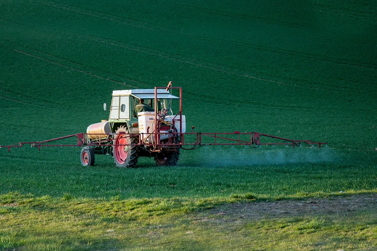 A tractor spraying treatment across a green field