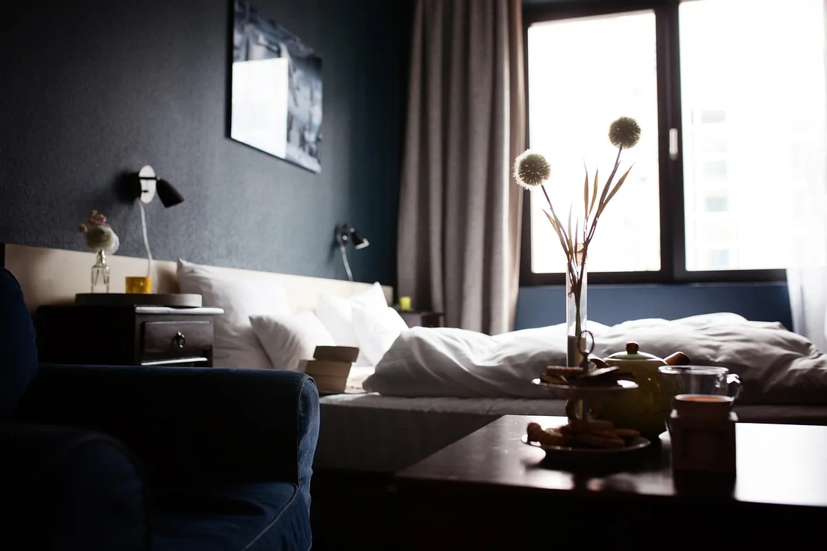 A neatly made hotel bed beside a window