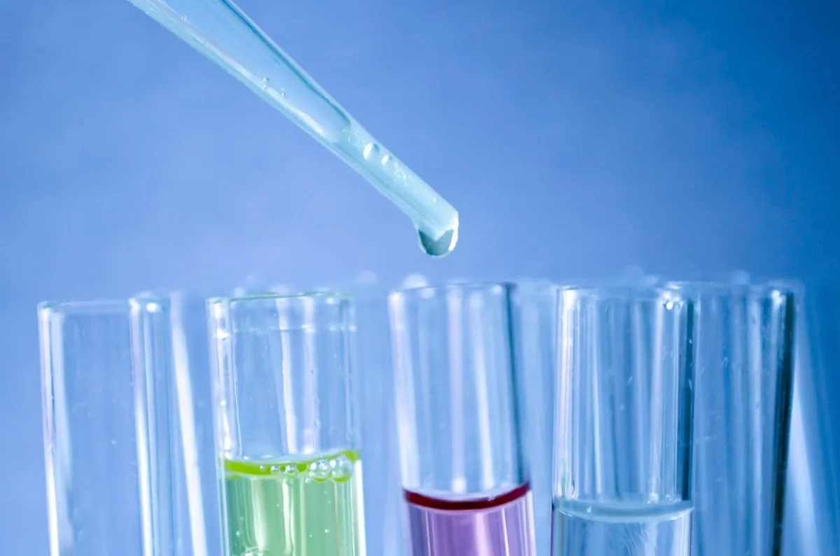 A gloved hand using a pipette in a laboratory