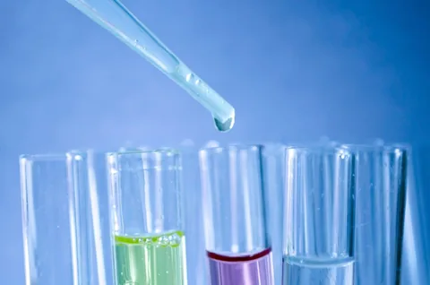 A gloved hand using a pipette in a laboratory