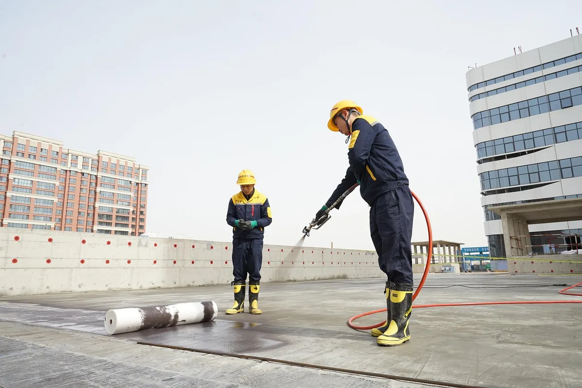 Workers in protective gear spraying a building exterior