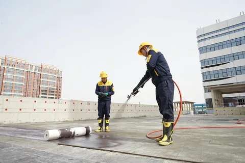 Workers in protective gear spraying a building exterior