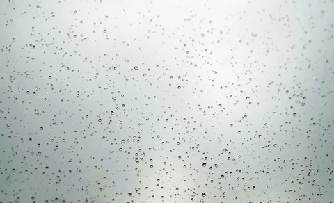 Rain droplets running down a window pane