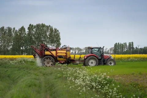 A sprayer applying treatment outdoors along a field