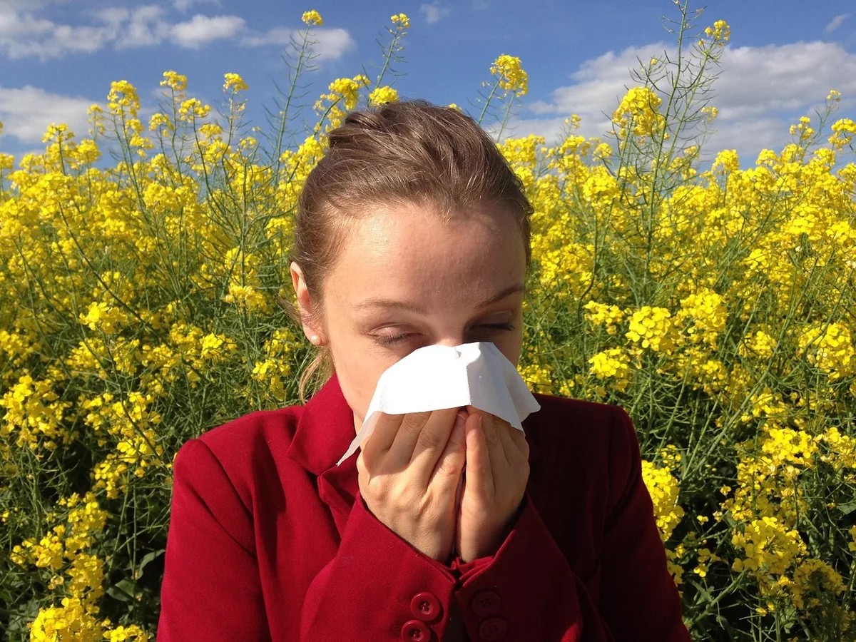 A person sneezing into a tissue at home
