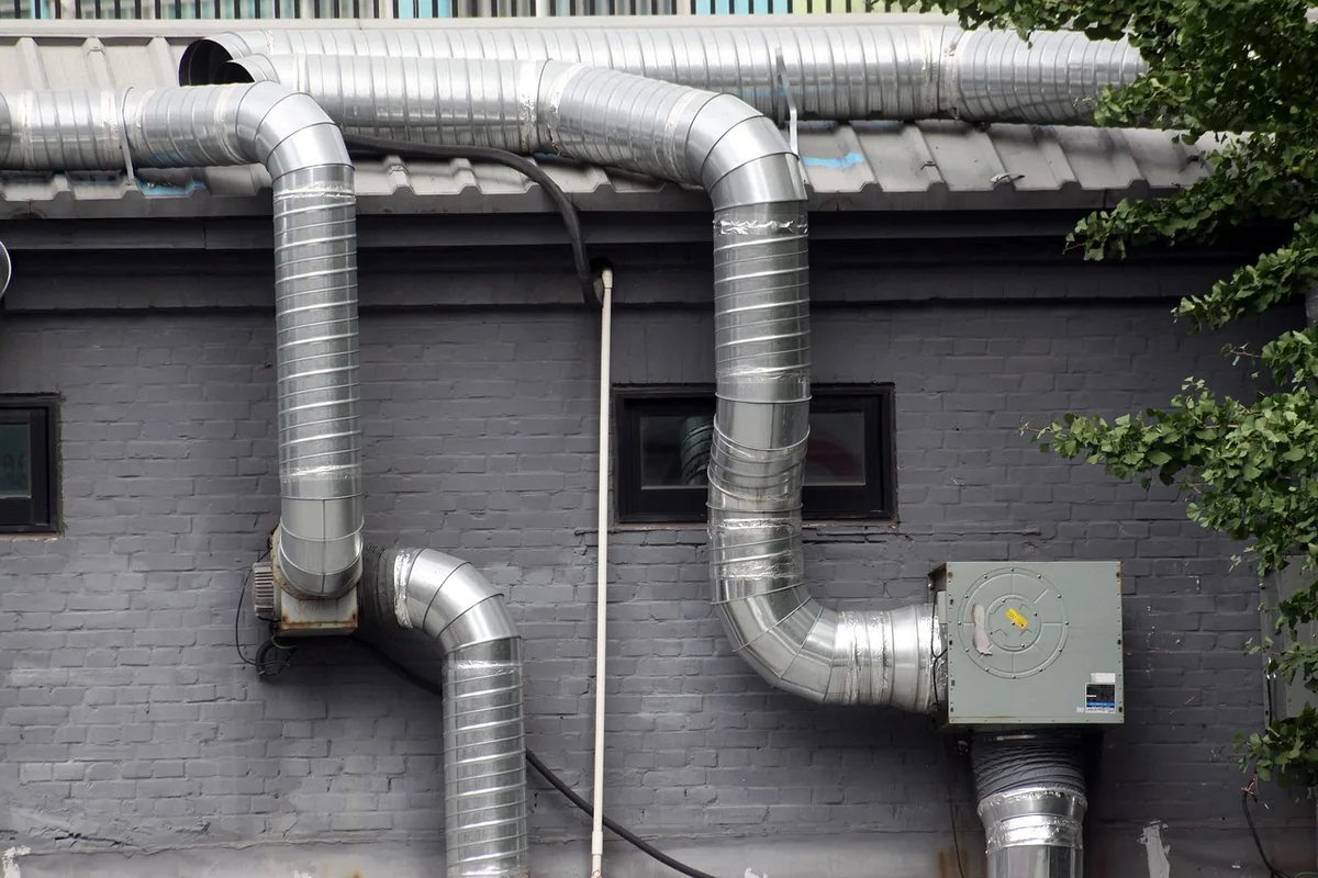 Pipes and a vent along a house foundation